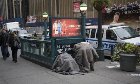 A homeless man huddles with his possessions by a subway entrance on 8th Avenue in New York City.