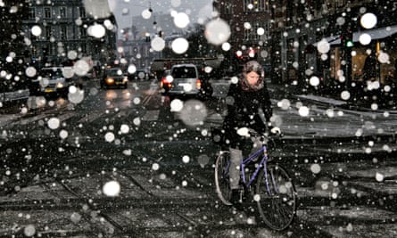 A woman rides her bike in heavy snow in Copenhagen.