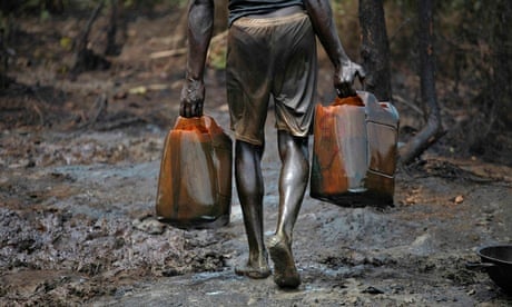 A man carries oil at a refinery in Bayelsa, Nigeria