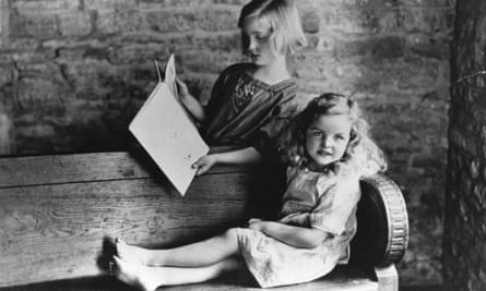 Unity Mitford, nine, reading with sister Jessica, six, in the garden of their house in Asthall.