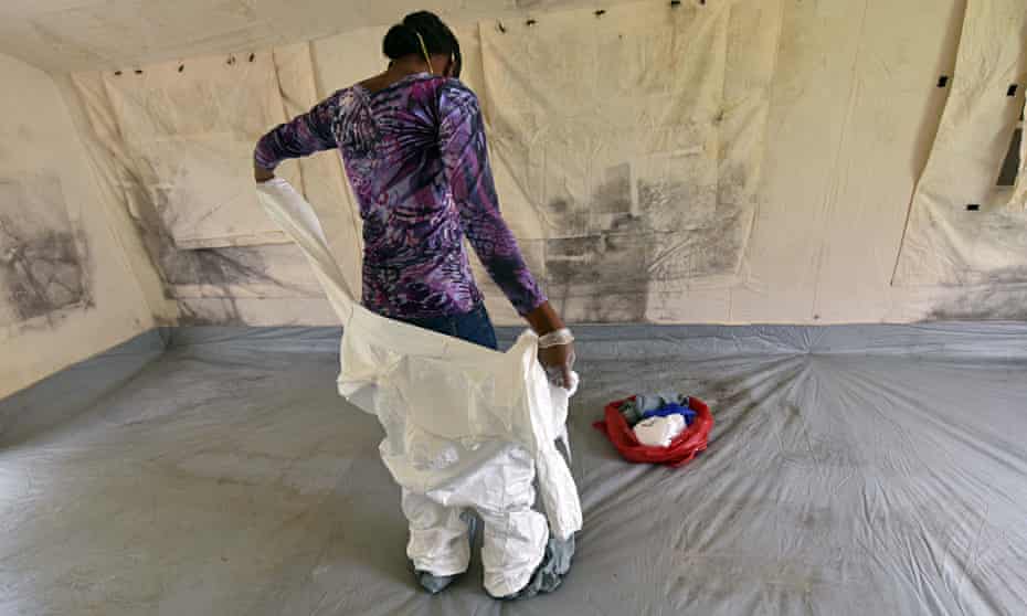 A health worker removes her protective gear inside a tent in an Ebola unit in the Ivory Coast