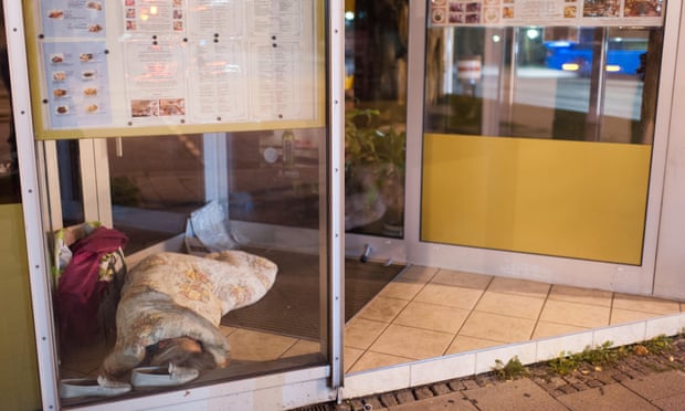 A homeless person sleeps in the entrance to a restaurant in Munich.