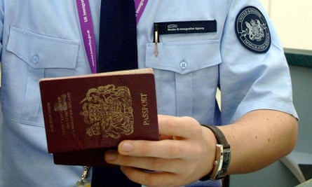 An immigration officer checking a passport from a passenger arriving at Heathrow airport.