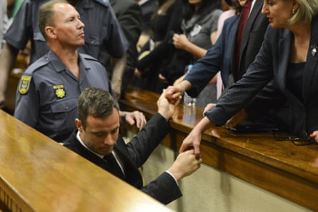 Oscar Pistorius holds the hands of family members as he is taken down to the holding cells after being sentenced to five years' imprisonment.