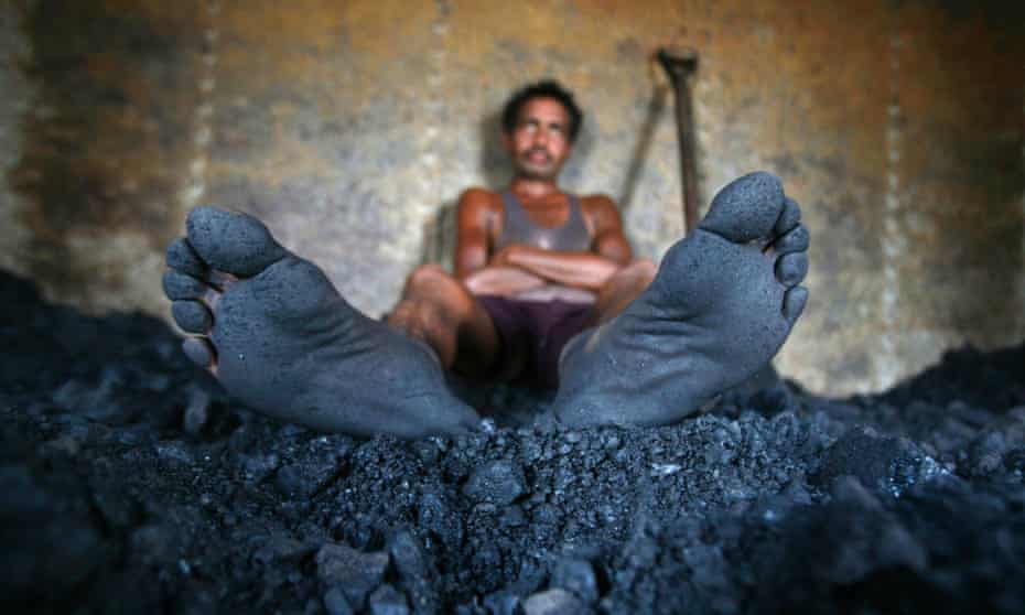 A labourer takes a break from shovelling coal at a coal yard on the outskirts of Jammu .