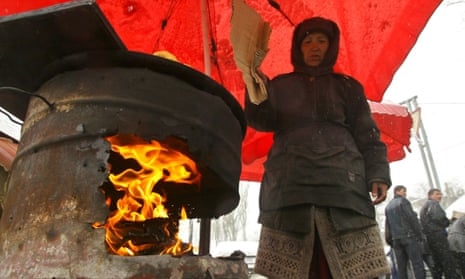 A street vendor keeps a fire in a makeshift oven to warm traditional bread for sale at a city market in Bishkek, Kyrgyzstan, 2005.