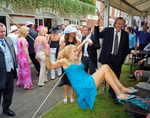 A female visitor to Royal Ascot hangs from the support of a hospitality tent. June, 2002.