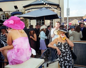A woman dressed for Ladies Day drinks from a plastic pint glass outside a pub next to Royal Ascot Racecourse. June, 2001.