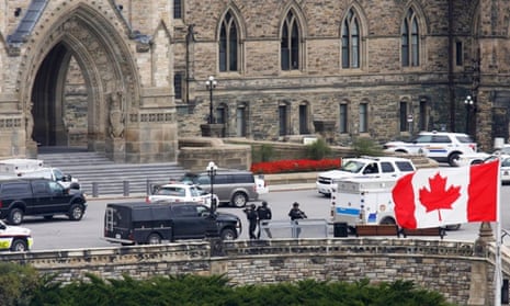 Armed RCMP officers approach Centre Block on Parliament Hilll following a shooting incident in Ottawa