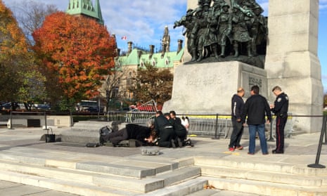 Police, bystanders and soldiers aid a fallen soldier at the War Memorial in Ottawa.