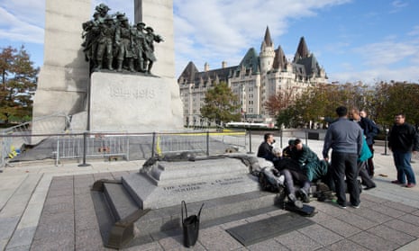 Police, bystanders and soldiers aid a fallen soldier at the War Memorial in Ottawa.