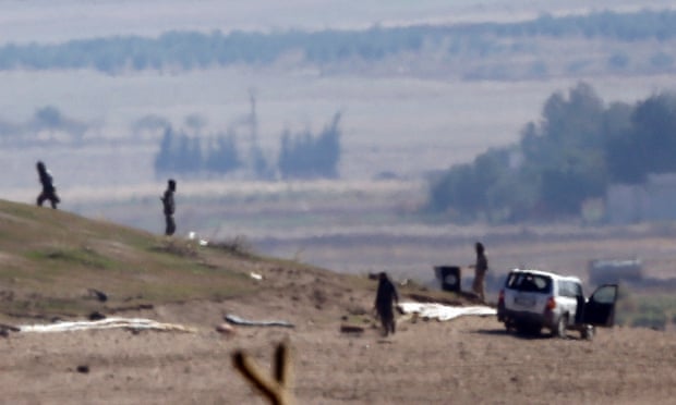 Isis fighters inspect a hill on the outskirts of Kobani