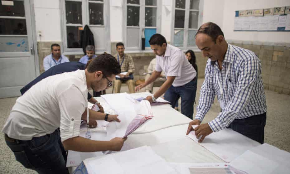 Electoral workers count ballots at a polling station in Tunis.