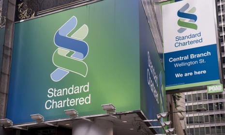 Standard Chartered billboards hang above a bank branch in Hong Kong.