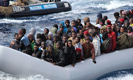 Migrants sit in a boat off the coast of Sicily during a mission by the Italian navy as part of its M