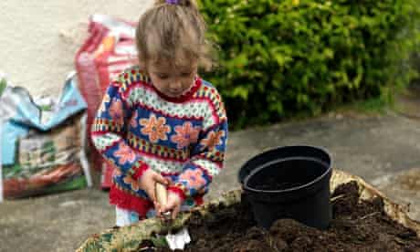 A Six year old Girl Filling up a Pot with Compost 