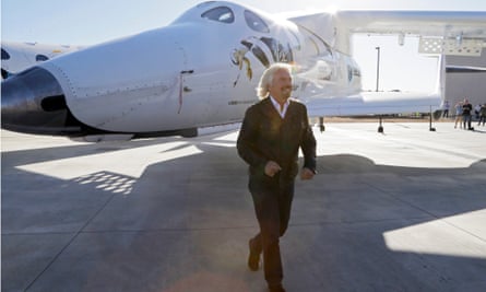 Richard Branson passes a SpaceShipTwo rocket under its mother ship at a Virgin Galactic hangar at Mojave Air and Space Port in Mojave, California.