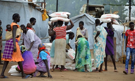 Women carry sacks of maize flour at a food distribution point in Juba, South Sudan