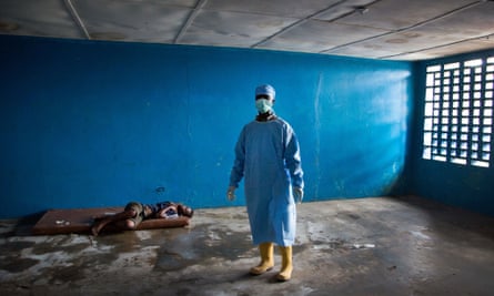 A healthcare worker stands next to a woman who has died of Ebola related symptoms in West Point, Monrovia, Liberia.