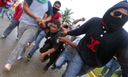 Demonstrators hold a riot police officer during clashes following a protest in Acapulco.