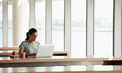 Young woman at row of desks with open laptop and apple