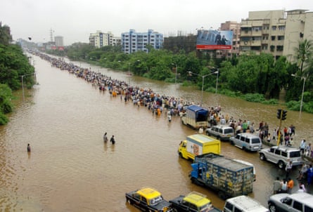 Indian commuters walk through floodwaters 27 July 2005 after torrential rains paralysed the city.