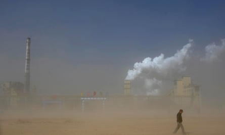 A man walks past a coal plant amidst a dust storm in Lingwu, Ningxia Hui Autonomous Regio.
