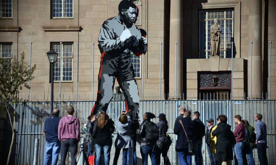 Tourists stand beneath The Shadow Boxer, a public art commission in Johannesburg.