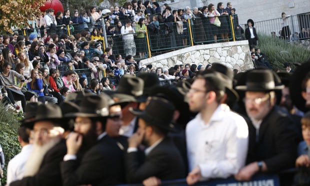 Ultra-orthodox Jews watch emergency personnel clean up and secure the area of the attack.