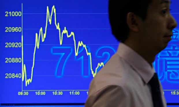 A man walks past a television monitor showing a drop in Hong Kong's benchmark Hang Seng Index