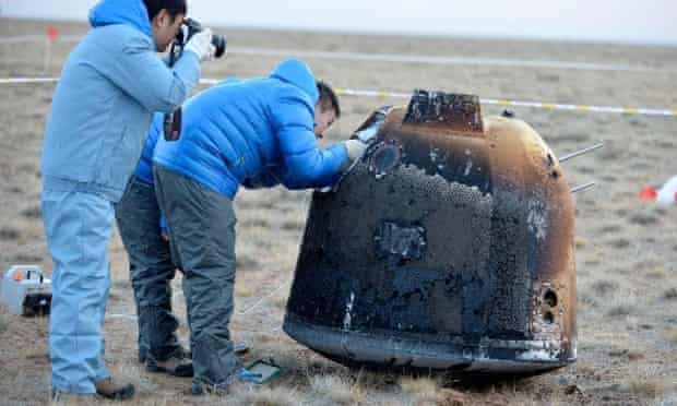 Chinese researchers examine the scorched Chang'e 5-T1 return capsule after it landed successfully in Inner Mongolia having travelled around the moon and back.