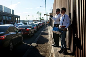 Musicians play for motorists as they wait to cross the border into the US, Mexicali, Mexico