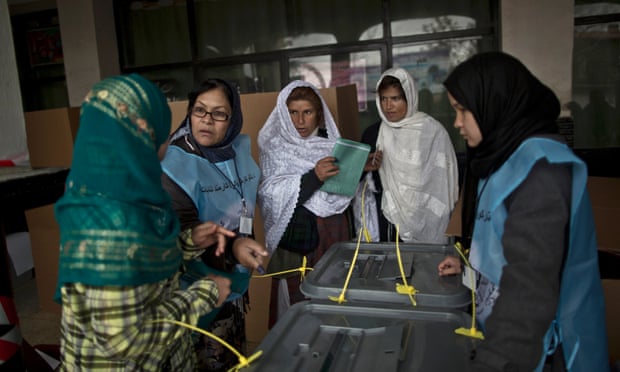 An Afghan election worker, second left, explains the process of elections to voters at a polling station in Kabul, Afghanistan, on April 5, 2014. Afghan voters lined up for blocks at polling stations nationwide on Saturday, defying a threat of violence by the Taliban to cast ballots in what promises to be the nation's first democratic transfer of power.