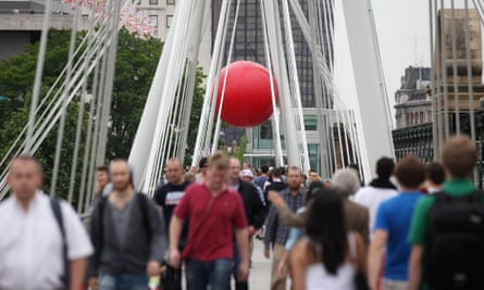 Members of the public walk beneath artist Kurt Perschke's installation 'RedBall' on the Golden Jubilee footbridge in London.