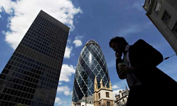A man passes the Swiss RE building (known as the Gherkin) in the City of London