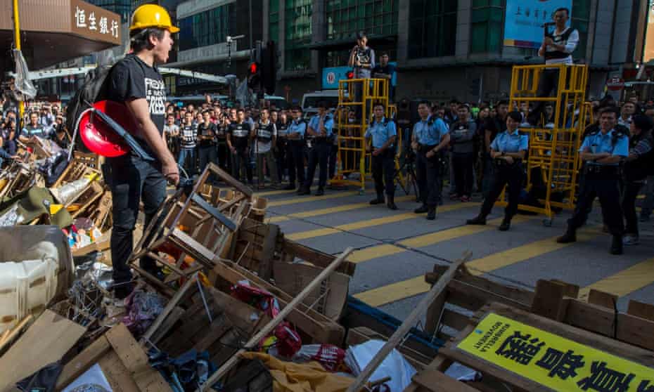 A pro-democracy protester stands on top of barricades as police arrive to dismantle the Mong Kok protest site in Hong Kong.