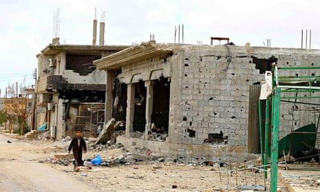 A boy walks next to the ruins of buildings near Benghazi