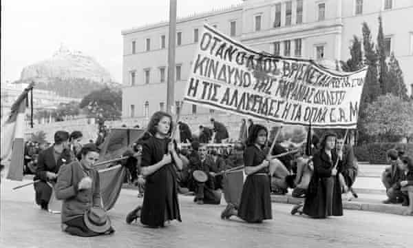 Tre donne in ginocchio in una strada con uno striscione di protesta contro le sparatorie