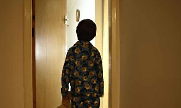 Six year old boy stands in corridor in pyjamas with teddy bear