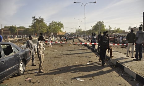 People gather at the site of a bomb explosion in Kano