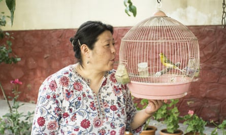 Hiromi Yasui in her garden with a bird in a cage