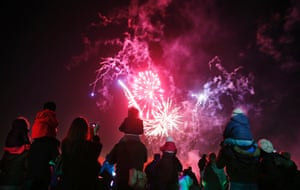 Children sit on their parents' shoulders as they watch a bonfire night firework display at Roundwood Park in northwest London