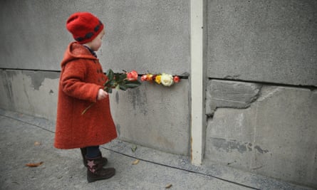 Hulda, 3, places flowers in between slats of the former Berlin Wall at the Berlin Wall Memorial at Bernauer Strasse.