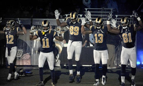 Members of the St. Louis Rams raise their arms as they walk onto the field before an NFL game against the Oakland Raiders.