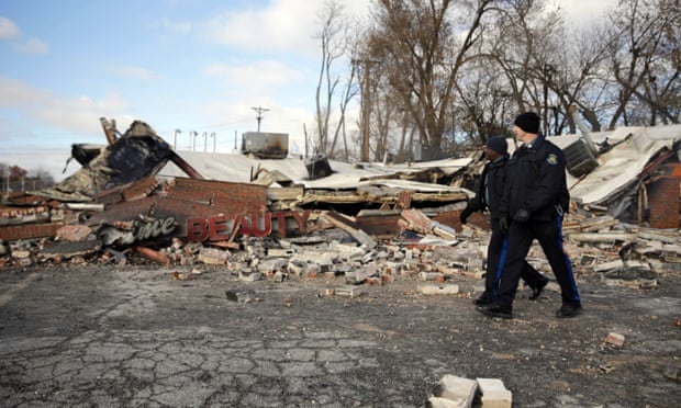 Members of the Missouri Highway Patrol walk past a building burned to the ground in Ferguson.