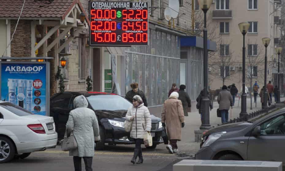 People walk past a display with currency exchange rates in central Moscow, Monday, Dec. 1, 2014.