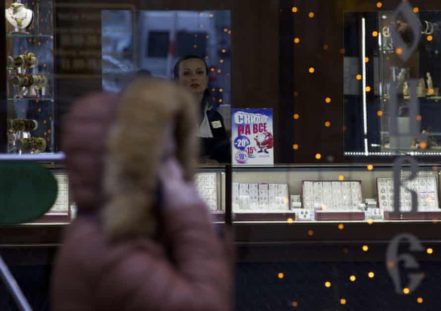 A saleswoman waits for customers in a jewerly shop with a poster reading "Sales on everything" in downtown Moscow, Russia, Monday, Dec. 01, 2014.