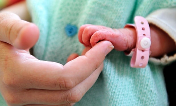 A newborn baby holding the finger of his mother