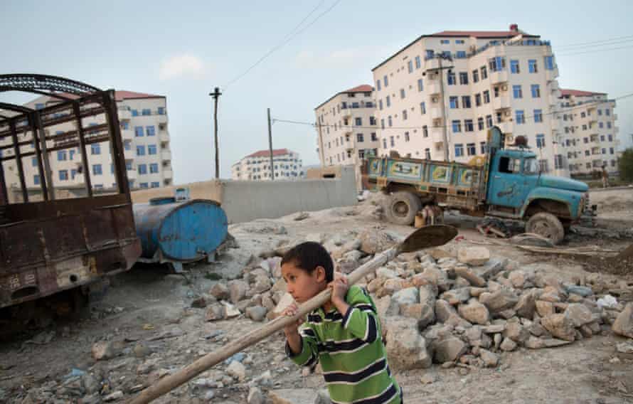 A boy helps make bricks for new apartment blocks next to Aria City, a gated high-end residential complex.