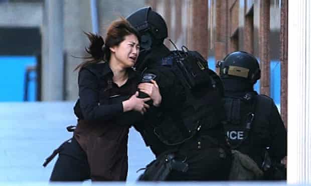 Sydney, Australia A hostage runs to armed tactical response police officers for safety after she escaped from a cafe under siege at Martin Place in the central business district